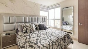 A bedroom with a bed, a nightstand, a large mirror, and a door. - Luxo no Vale do Lili (Cali)