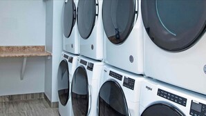 A row of stacked front-loading washing machines in a laundry room.