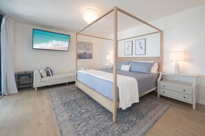 A four-poster bed with a view of the ocean, a sofa, a nightstand, and a wall-mounted TV. - 17th-Floor Gulf View Condo | Heated Pool, Hot Tub (Panama City Beach)