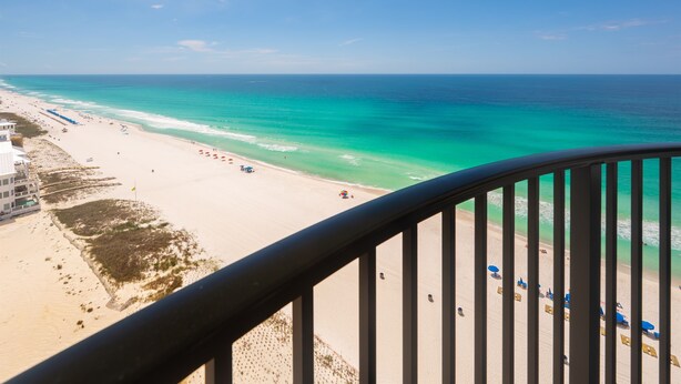 A beach view from a balcony with a railing, sandy beach, and ocean. - Gulf View Oasis and Beach Chairs (Panama)