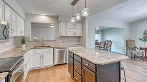 Una cocina moderna con armarios blancos, encimera de granito y lavavajillas integrado.