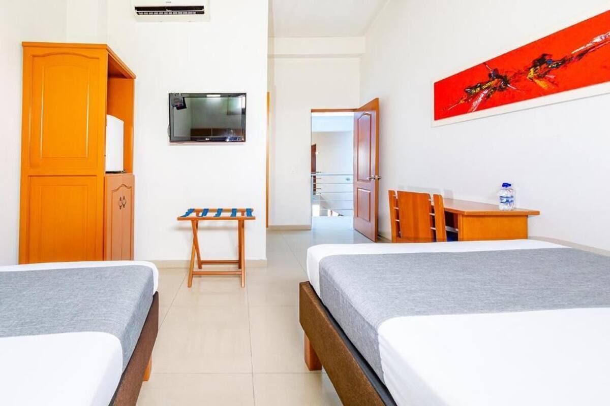 Habitación de hotel con dos camas, televisión, escritorio, silla y armario.