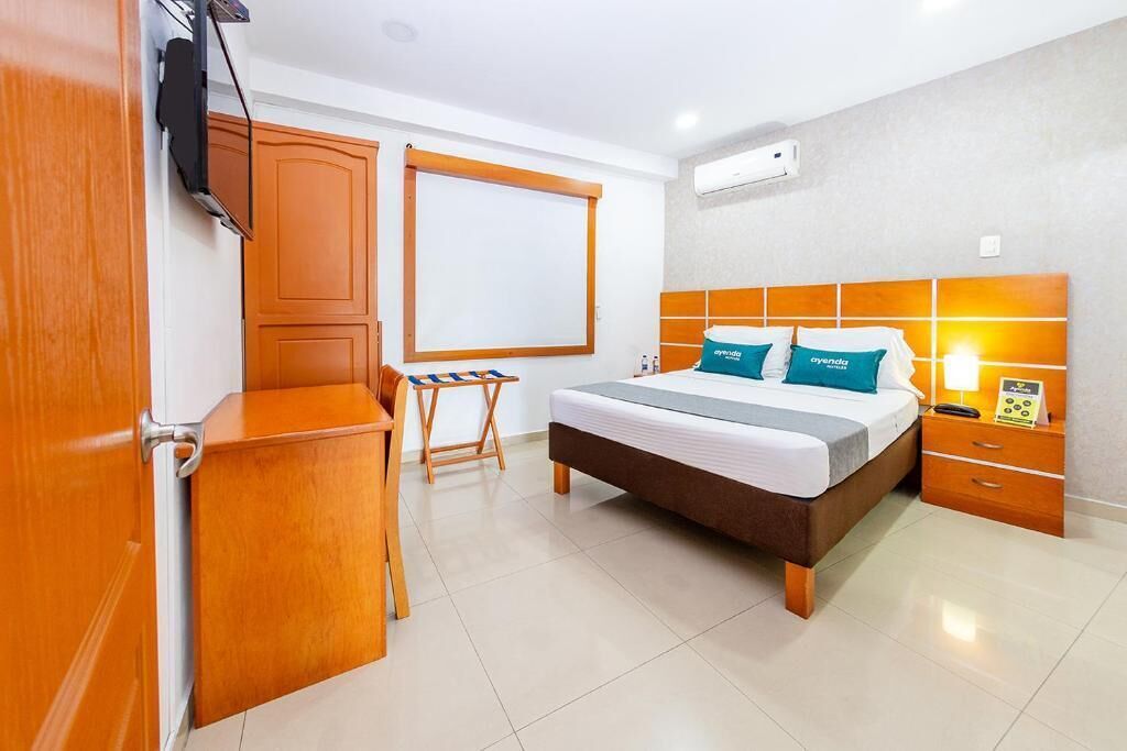 Une chambre d’hôtel comprenant un lit, un bureau, une chaise, une télévision, une table de chevet et une petite table.