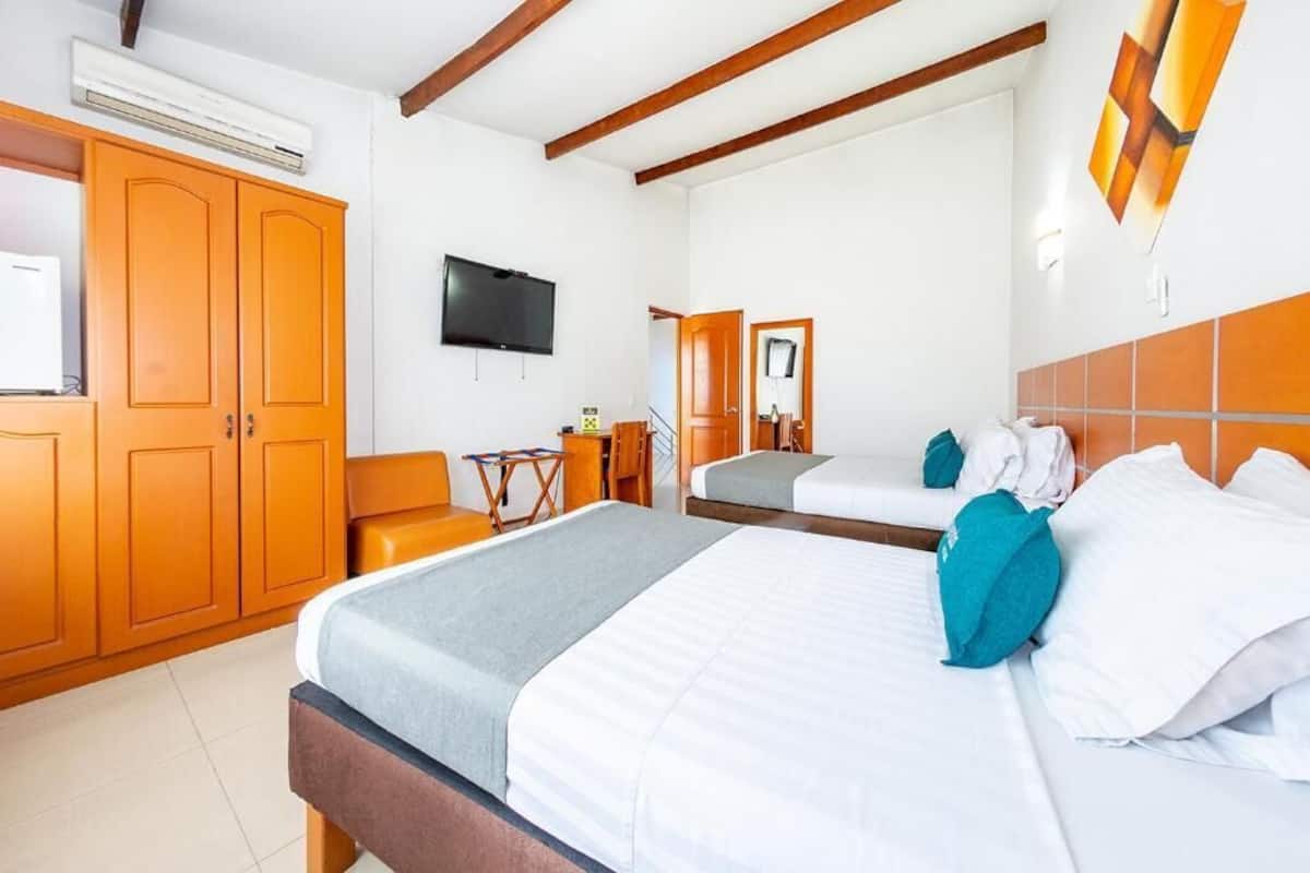 Una habitación de hotel con una cama grande, un escritorio, una silla, un televisor y un armario.