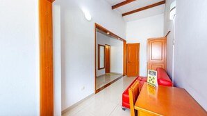 A hallway with a wooden door, a red bench, and a table with a sign.