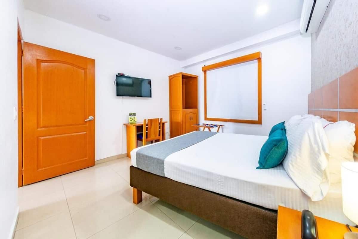 Una habitación de hotel con cama, televisión, armario y escritorio.