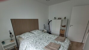 A bedroom with a bed, bedside table, lamp, wardrobe, and a door.