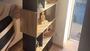 A multi-tiered wooden bookshelf with a plant on top, a Buddha statue, and a decorative tree shelf.