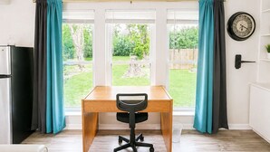 A room with a wooden desk, black office chair, and a clock on the wall.