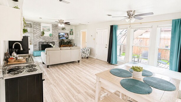 A modern kitchen with a dining area, a fireplace, and a view of the backyard.