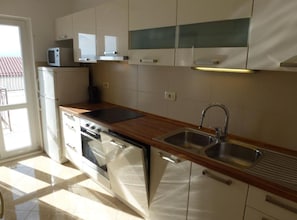 Eine moderne Küche mit eingebautem Backofen, Mikrowelle und Spüle aus Edelstahl.