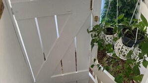 A white door with a white picket fence, a hanging plant with a white pot, and a white decorative item. - Comfort Studio Apartment - Studio Apartment with Garden View (Kastel Luksic)