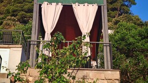 Une petite construction composée d'une seule pièce, avec une enseigne verte, un balcon doté d'une rambarde en métal et une vue sur les arbres.