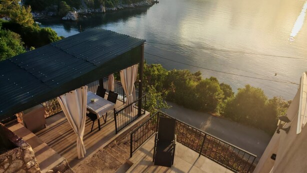 Une terrasse avec une table et des chaises, donnant sur une étendue d’eau et sur de la verdure.