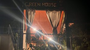 Une entrée d'immeuble avec une enseigne indiquant « GREEN HOUSE » et un escalier menant à l'étage.