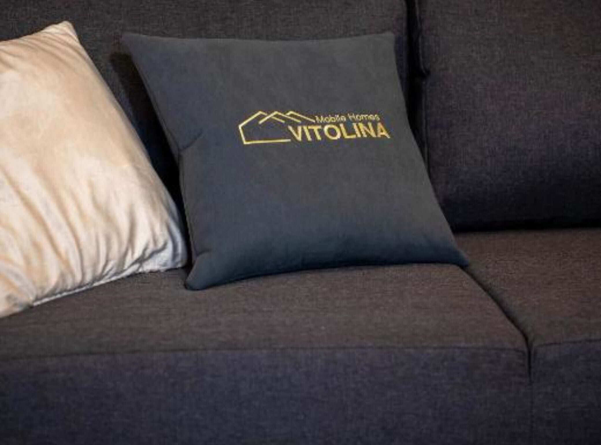 Un canapé gris foncé agrémenté d’un coussin orné d’un logo et d’un texte.