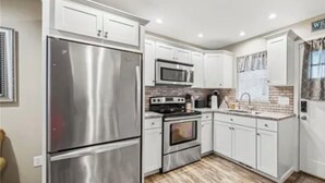 Una cucina moderna con elettrodomestici in acciaio inossidabile, mobili bianchi e una schiena di pavone a motivi a spina di pesce.