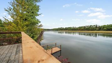 Une terrasse en bois s’étendant au-dessus d’un lac paisible, sous un ciel dégagé.