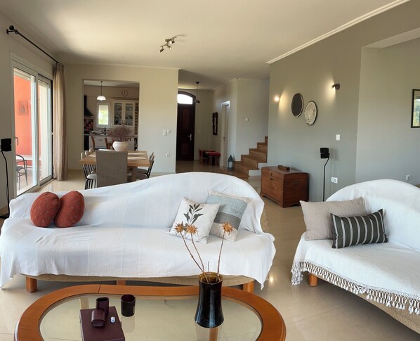 Ein modernes Wohnzimmer mit zwei weißen Sofas, einem Couchtisch und einer Vase mit Zweigen.