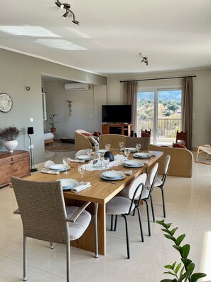 Een eetgedeelte met een houten tafel voor vier personen, omringd door rieten stoelen.