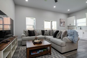 A modern living room with a sectional sofa, a coffee table, and a TV. - Brand New Duplex Near Downtown! (Greenville)