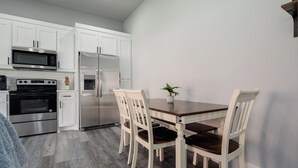 Una cocina moderna con armarios blancos, electrodomésticos de acero inoxidable y una mesa de comedor de madera con sillas.