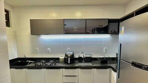 Una cocina moderna con armarios blancos, un refrigerador de acero inoxidable, una estufa a gas y un microondas.