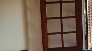 Una cama con cabecera, una mesita de noche con una figurita y una ventana con persianas.