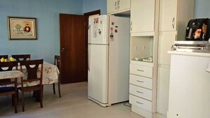 Una cocina equipada con refrigerador, microondas y tostadora. Hay una mesa de comedor con sillas.