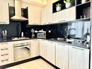 A modern kitchen with a built-in oven, microwave, and stainless steel sink. - Master Suite Rialto Residences (Santiago de los Caballeros)