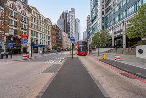 Eine Stadtstraße mit Busspur, Gebäuden und einem roten, zweistöckigen Bus.