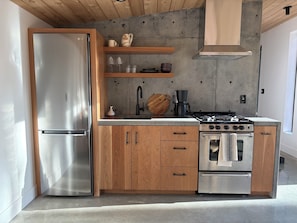Une cuisine moderne dotée d’un réfrigérateur en acier inoxydable, de meubles de rangement en bois, d’une cuisinière à gaz et d’un four encastré.