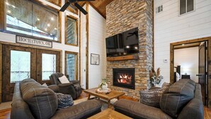 Ein gemütliches Wohnzimmer mit Ledersofas, einem Kamin und einer Wand aus Stein.