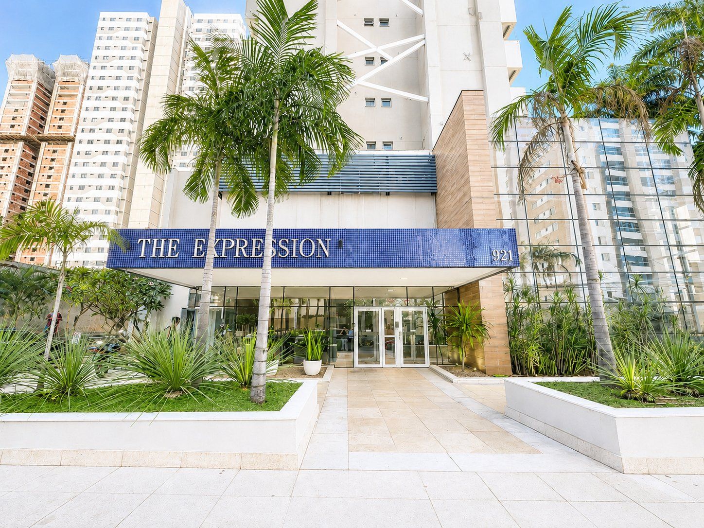 Entrada de un hotel con un letrero azul que dice 'THE EXPRESSION 921'.