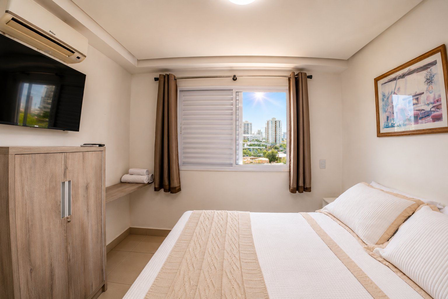 A bedroom with a bed, a TV, a window with curtains, a painting, and a cabinet.