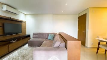 A modern living room with a sectional sofa, a flat-screen TV, and a wooden entertainment unit.