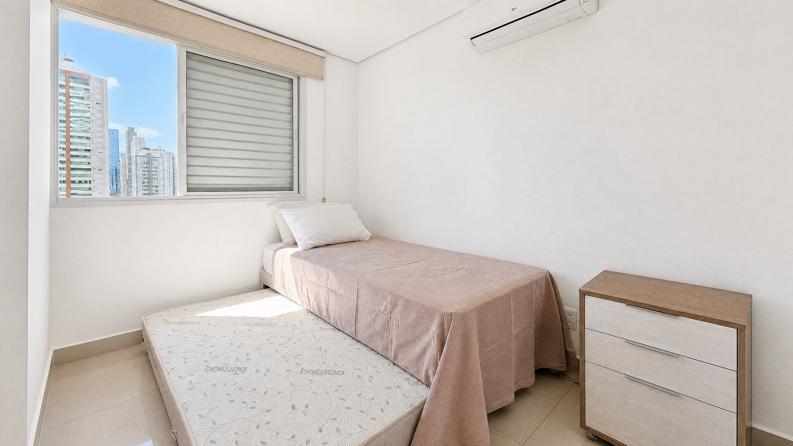 A bedroom with a bed, a bedside table, a dresser, and a window with blinds.