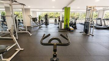 A gym with exercise equipment, a treadmill, and a green pillar.