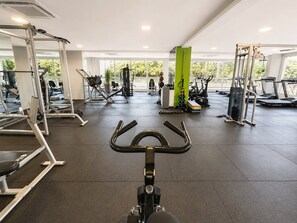 Ένα γυμναστήριο με όργανα γυμναστικής, έναν διάδρομο και έναν πράσινο κολόνα.