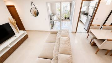 Una sala de estar moderna con sofá, televisión y comedor.
