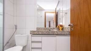 Une salle de bain comprenant des toilettes, une douche, un meuble-lavabo avec un miroir et une porte en bois.