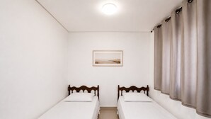A room with two single beds, a framed picture on the wall, and a window with curtains. - The Expression 2 Quartos (Goiânia)