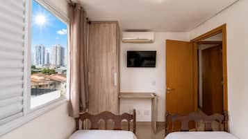Een slaapkamer met twee bedden, een televisie, een airconditioning en uitzicht op de stad.
