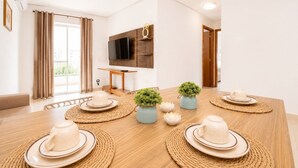 Un espace repas moderne avec une table en bois, des sets de table en fibres tressées et des plantes décoratives.