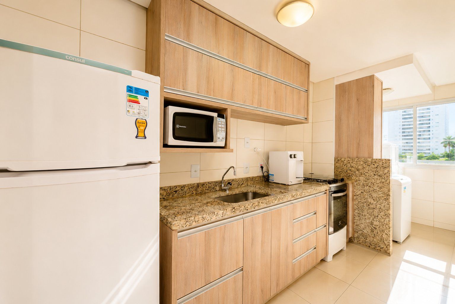 Una cocina moderna equipada con refrigerador, microondas, cafetera y estufa.
