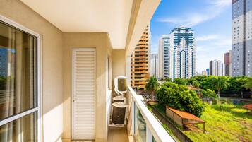 Een balkon met uitzicht op hoge gebouwen, een deur en een airconditioning.