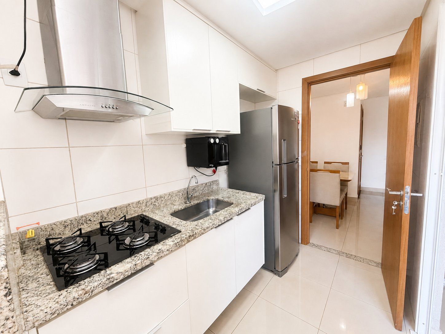 Una cocina moderna con armarios blancos, un refrigerador de acero inoxidable, una estufa a gas y un microondas integrado.