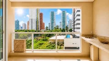 Un balcón con vista a la ciudad, un lavamanos y una cesta decorativa.