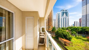 A balcony with a view of tall buildings, a door, and an air conditioning unit. - The Expression 2 Quartos (Goiânia)