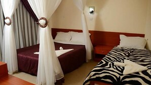 A hotel room with two beds, a wooden nightstand, a bedside table, and a wall-mounted light fixture.